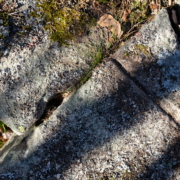 Detaljbild på spår efter användning av bredkil och rits. Från delar av momentet att klyva berget. Kilar slogs ner i borrhål, ofta längs en inhuggen rits för att få berget att spricka längs med önskad riktning. I ett stenbrott beläget i utredningsområdets norra del. Foto mot nordost.
